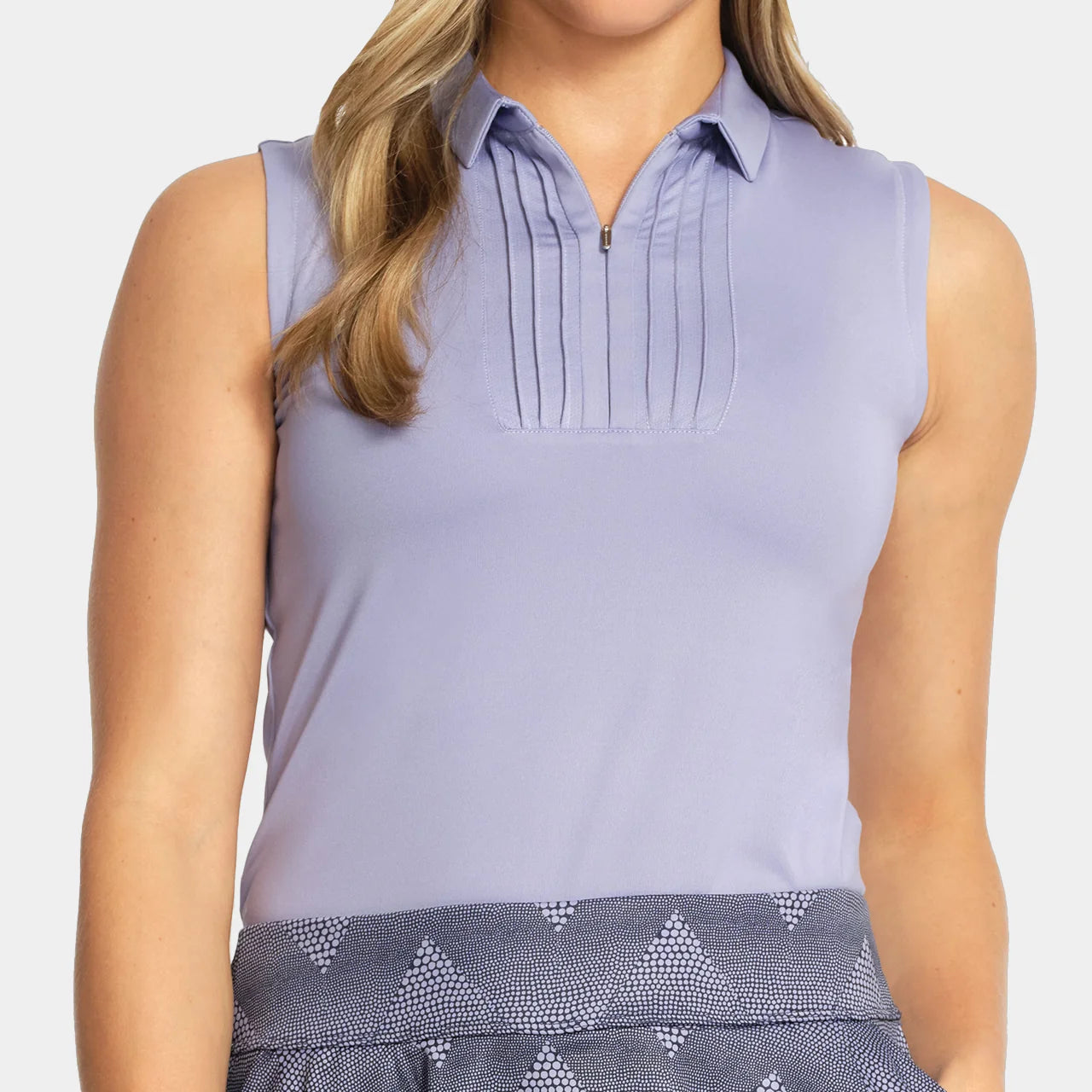 Woman wearing a light purple sleeveless blouse with patterned bottoms on a white background