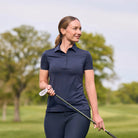 Woman in navy blue golf attire holding a golf club on a golf course.