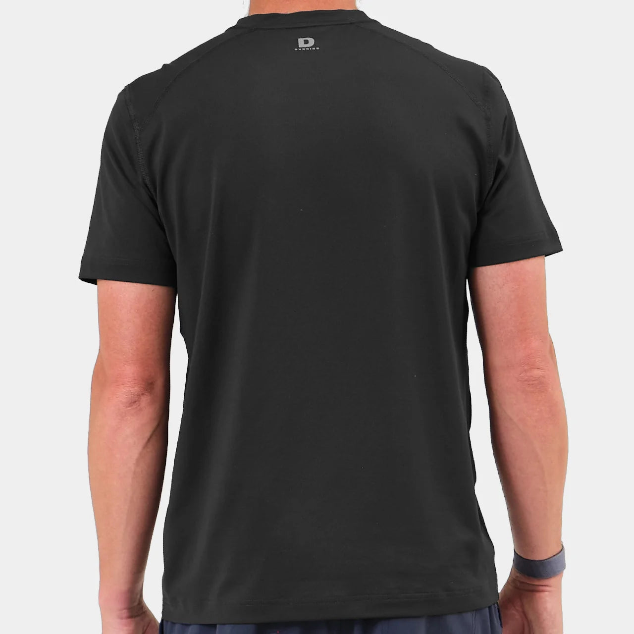 The back of a black t-shirt worn by a person on a light gray background
